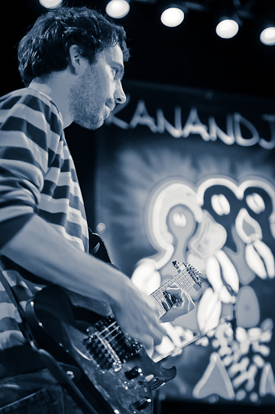 Le guitariste du groupe Kanandjo avec l'affiche en fond
