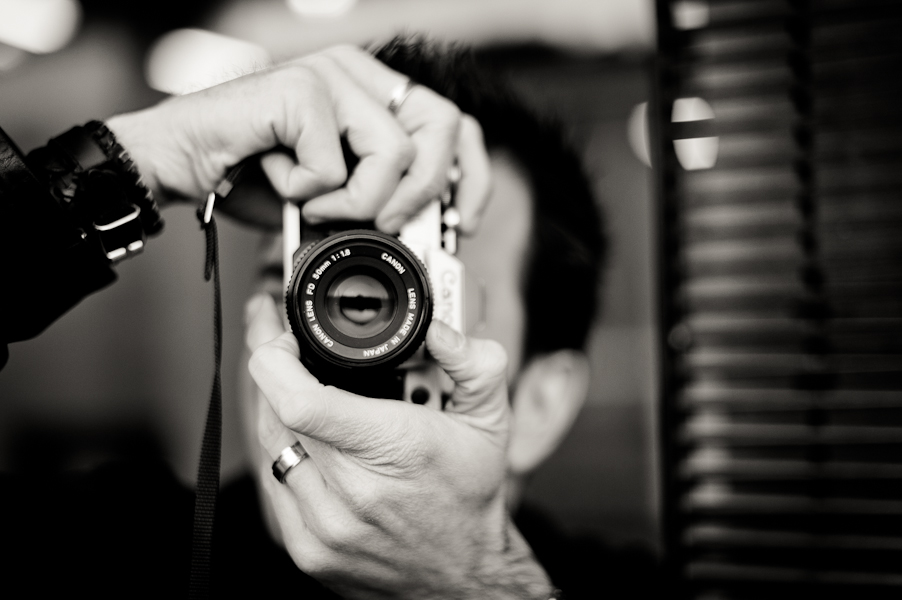 Gros plan en noir et blanc sur un homme utilisant un appareil photo argentique avec un 50mm