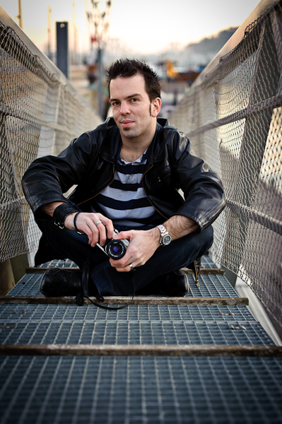 Portrait d'un homme avec son appareil argentique assis sur un ponton d'amarrage 