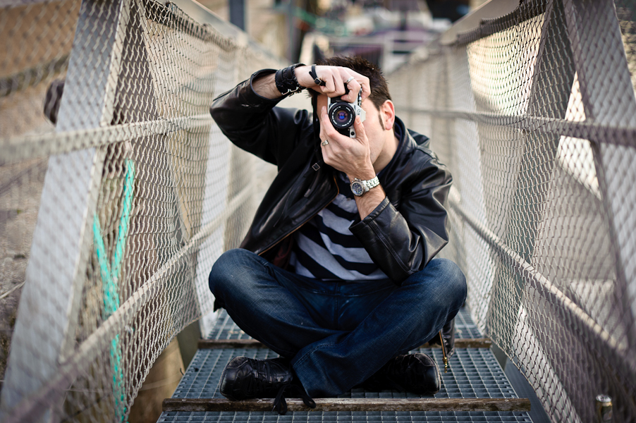 Portrait d'un homme photographiant à l'argentique assis sur un ponton d'amarrage